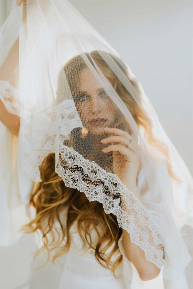 Model peers from behind wedding veil. Finding your style in wedding photography