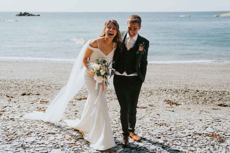 Bride and Groom laugh for portraits by the sea
