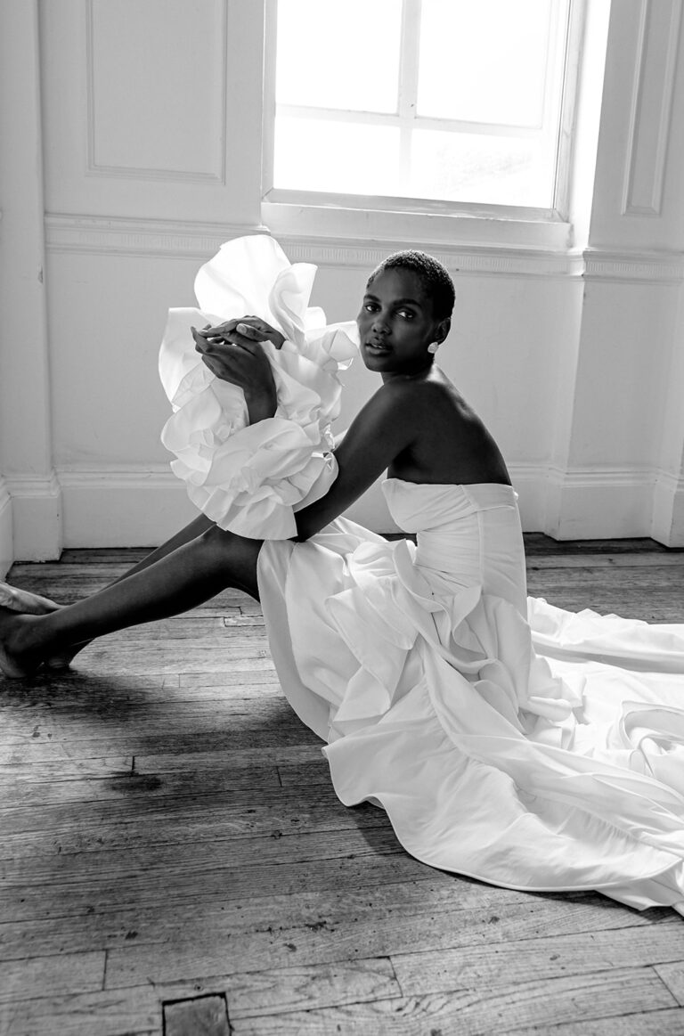 Black and white image of a model in a ruffled wedding dress crouched on the floor of a light filled studio taken by Tina Vedrine at Photography Farm's Thrive conference