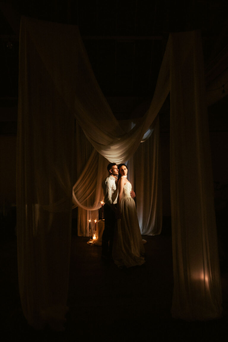 A bride and groom pose for a wedding portrait, a brilliant example of Drapery Wedding Trend Photography