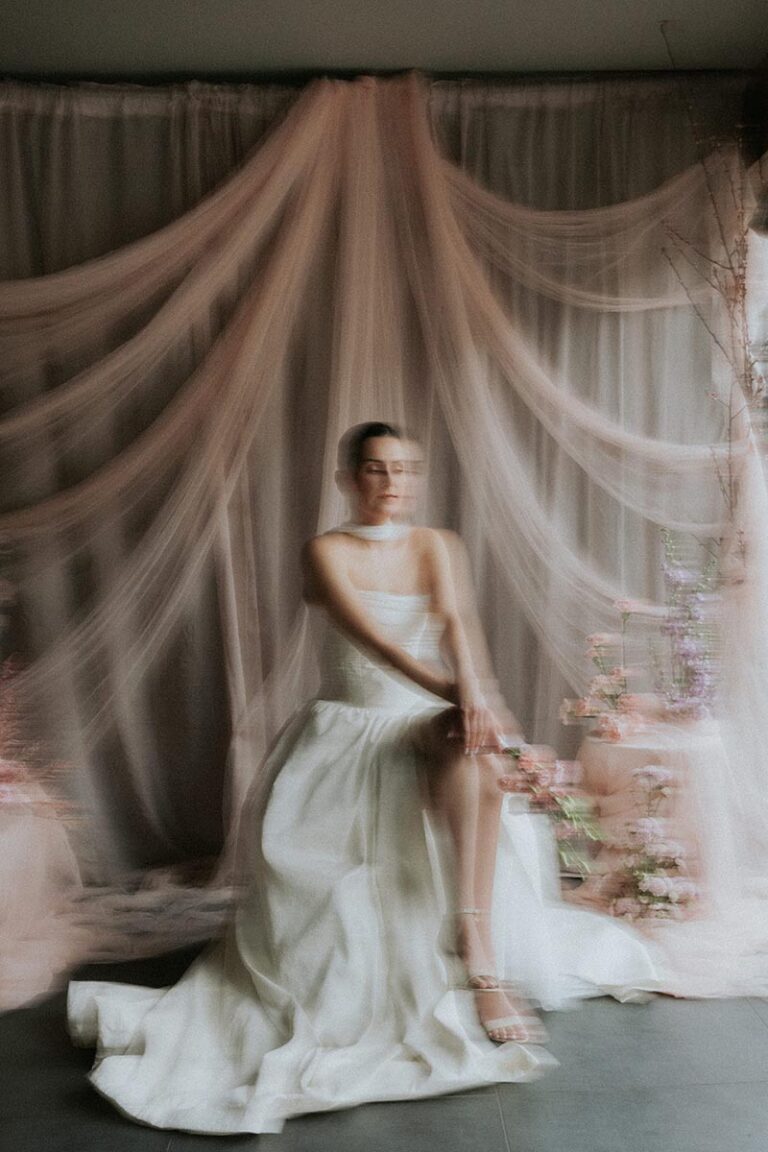 Bernadeta Kupiec Thrive Edinburgh Editorial - Bride Seated in Front of Draped Fabric and Flowers Bride seated gracefully in front of soft pink draped fabric and florals, photographed by Bernadeta Kupiec at Thrive Edinburgh.
