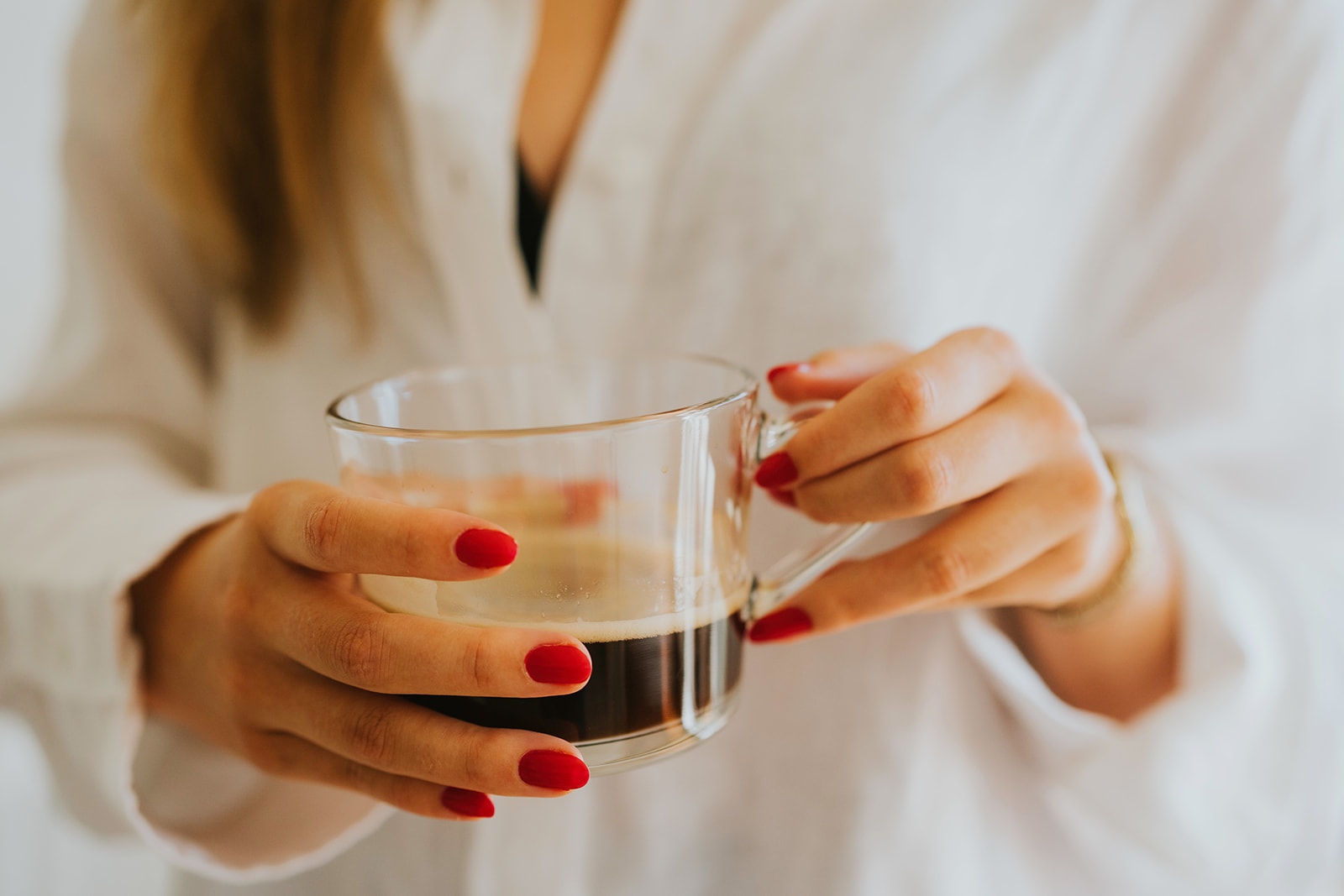 A close up of a woman holding a cup of black coffee, ready to start Culling Wedding Photos.