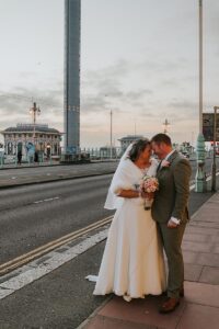 a couple on their wedding day on Brighton seafront for a post asking what is the best lens for wedding photography